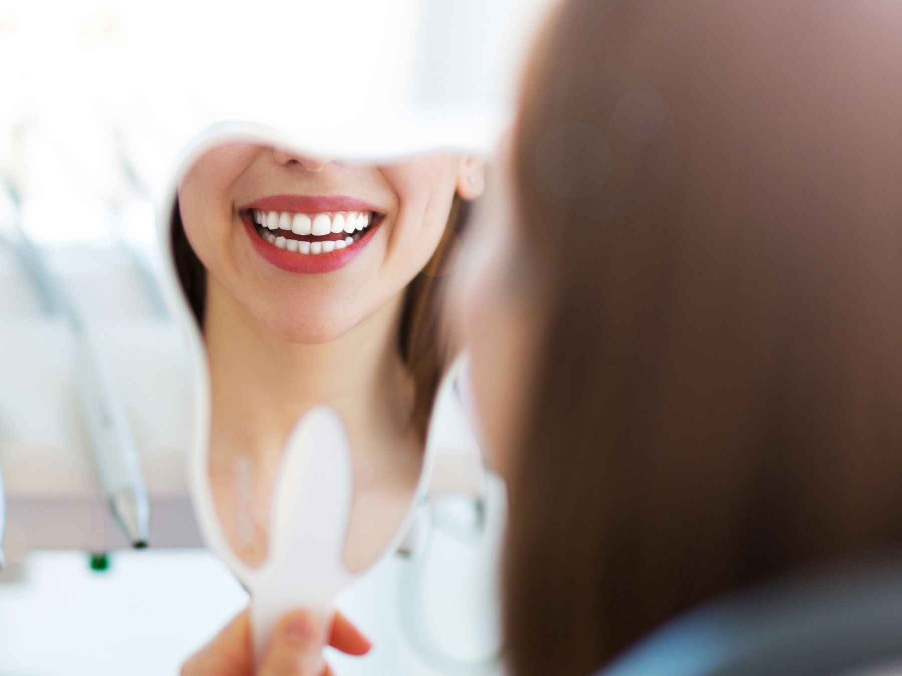 madison dentist patient model smiling into a tooth shaped mirror at a dental office